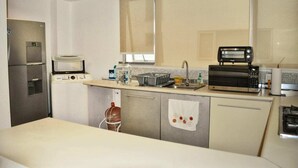 Une cuisine compacte équipée d’un réfrigérateur, d’un four à micro-ondes, d’un grille-pain et d’un petit évier.