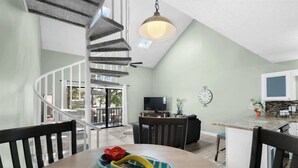 A modern kitchen with a built-in island, a dining area with a round table, and a spiral staircase. - Rudy's Reel 'Em Inn By Beach Star (Myrtle Beach)