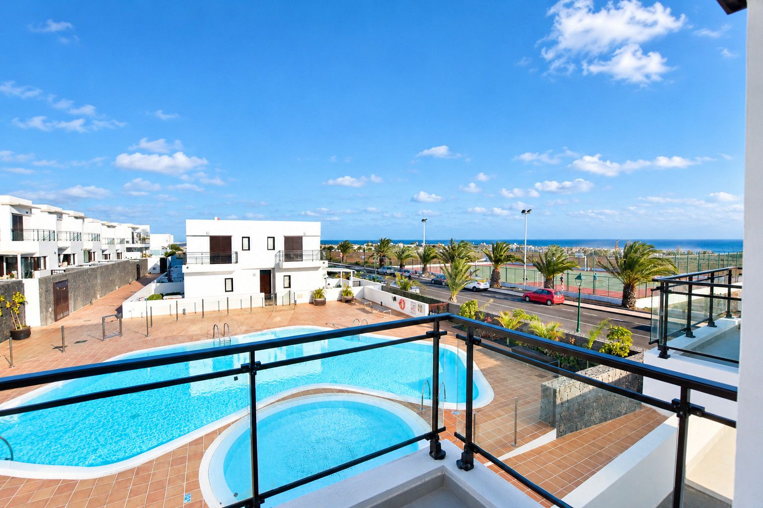 Una piscina en la azotea con vistas despejadas al mar y un complejo de edificios modernos al fondo.