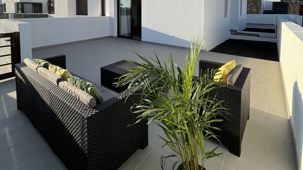 Eine moderne Dachterrasse mit Gartenmöbeln und Topfpflanzen.