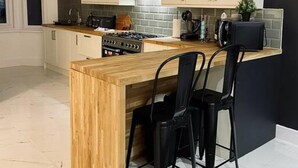 Una cocina moderna con isla de madera, sillas negras y armarios blancos.