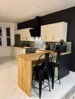 A modern kitchen with a wooden island, black chairs, and white cabinets.