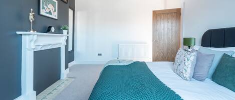 Un dormitorio con cama, chimenea, radiador y puerta de madera.
