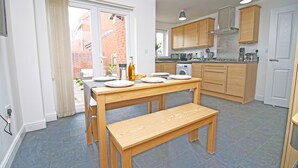 A modern kitchen with wooden cabinets, a dining table with benches, and a built-in oven.