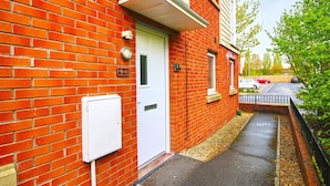 A red brick building with a white door, a small window, and a mailbox.