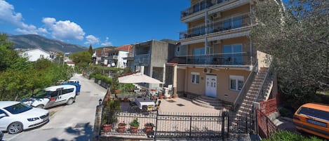 A multi-story building with balconies, a paved courtyard, and a view of the surrounding area.