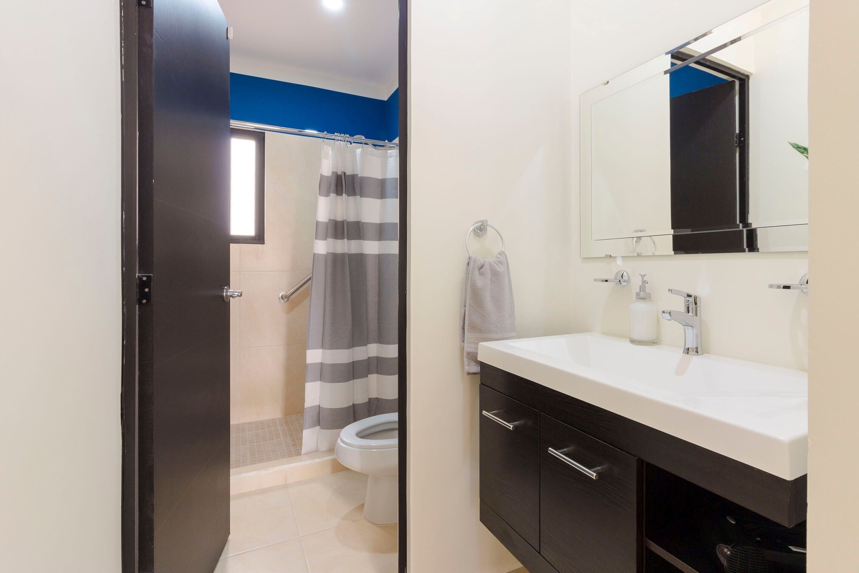 Ein Badezimmer mit Dusche, Toilette und Waschbecken inklusive Spiegel.