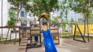 Een speeltuin met een blauwe glijbaan, houten klimconstructies en een klein onderkomen.