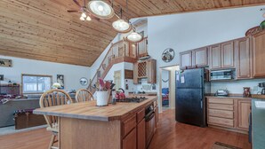 A spacious kitchen with wooden cabinets, a central island, and a staircase leading to an upper level. - Relax and cozy-in with friends at this spacious Graeagle cabin (Graeagle)