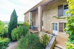 A stone building with a balcony, surrounded by greenery and a view of the countryside. - Mas Provence Gardoise (Uzès)- Swimming pool 12-6 m - 9 acres garden (Tresques)