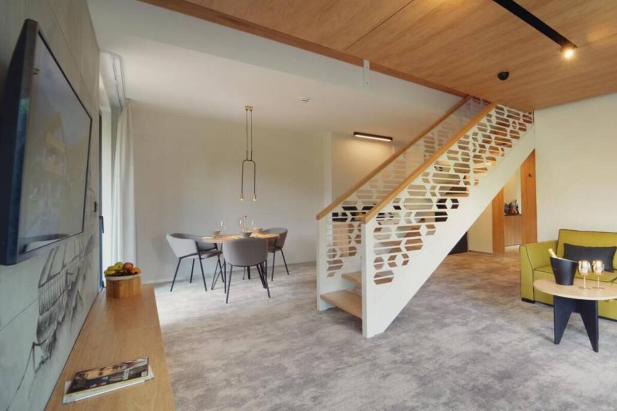 A modern living room with a staircase, a dining area, and a sofa.