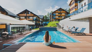 Una piscina techada, una piscina al aire libre, sombrillas