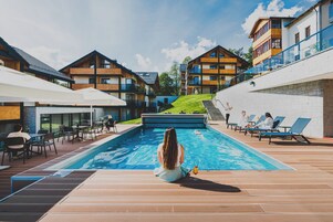 Una piscina techada, una piscina al aire libre, sombrillas