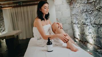 A person sitting on a bed in a spa-like setting with a stone wall and a massage table in the background.
