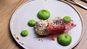 A dining table with a plate of food, a glass of white wine, and cutlery.
