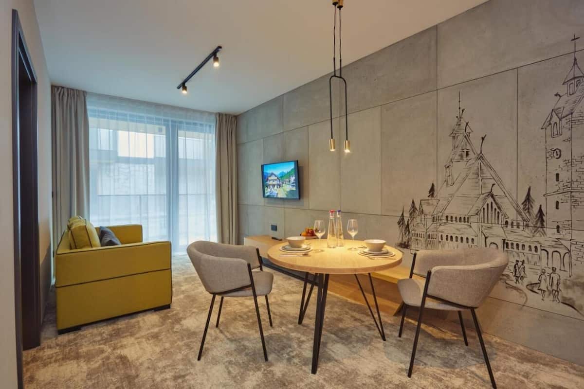 A modern dining area with a round table, chairs, and a television on the wall.