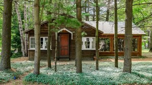 Un chalet rustique entouré de grands arbres et d’un jardin bien entretenu.