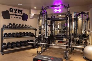 Une salle de sport équipée de matériel de musculation, d’haltères et d’un banc Reebok.