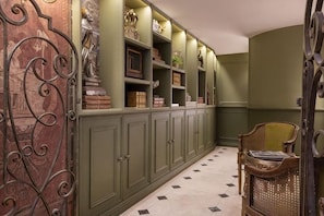 A hallway with green cabinets, a wicker chair, and a patterned floor. - Maison Cardinal Furstemberg (Paris)
