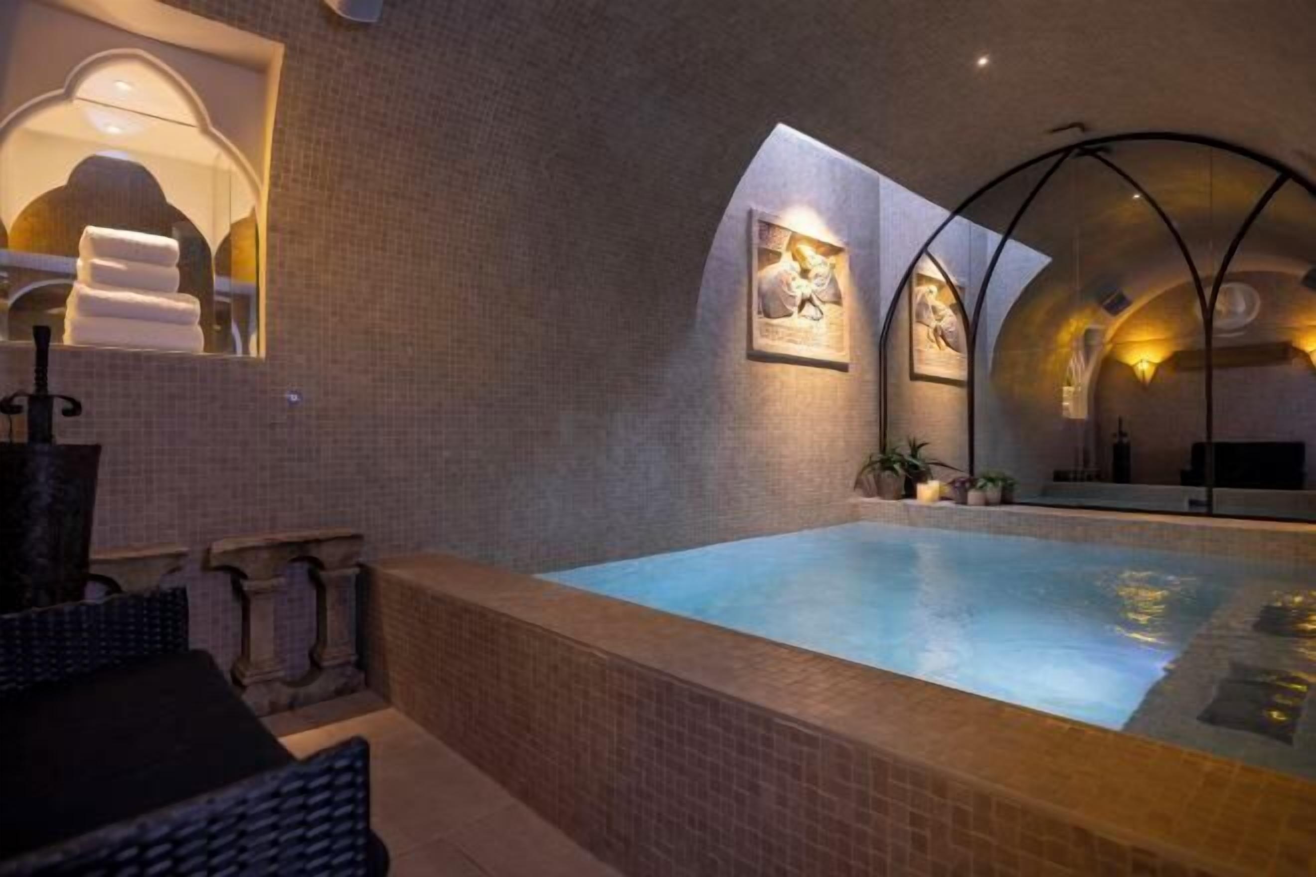 A spa area with a hot tub, tiled walls, and framed artwork.