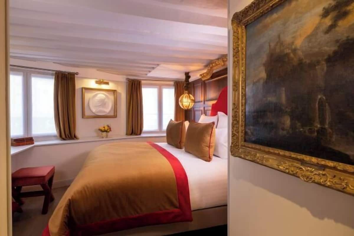 Ein Hotelzimmer mit einem großen Bett, einem Bild an der Wand und einem Fenster mit Vorhängen.