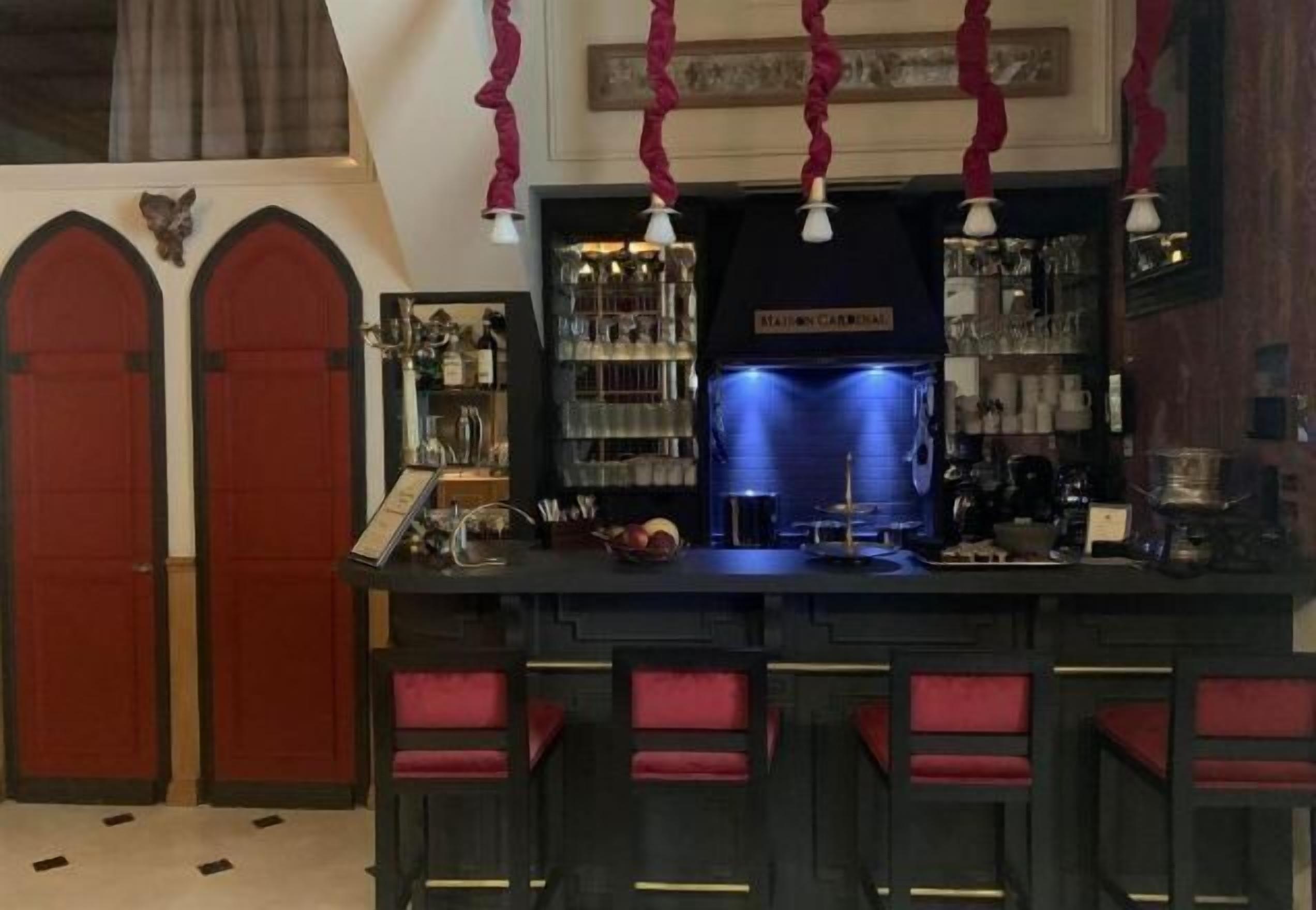 Uma área de bar com balcão, banquetas e um refrigerador iluminado em azul.