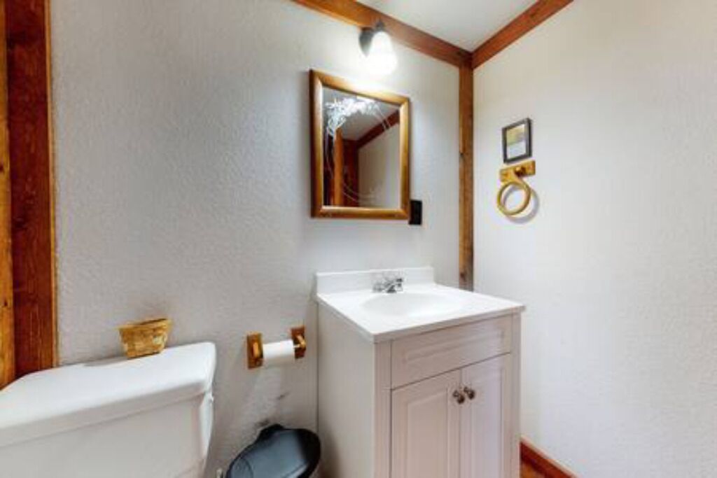 Et badeværelse med toilet, vask og spejl.