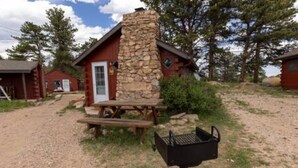 A rustic cabin with a stone chimney, a picnic table, and a grill. - Marr's Mountain Cabins - Cabin 3 (Red Feather Lakes)
