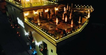 Un hotel con terraza exterior, sombrillas y zonas de estar.