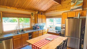 A wooden interior with a kitchen, dining area, and a large window.