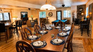 A dining room with a long wooden table set for a meal, surrounded by chairs.