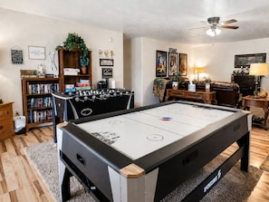 Ein gemütliches Wohnzimmer mit Kicker, Bücherregal, Couchtisch und Deckenventilator.