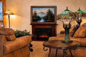 Ein gemütliches Wohnzimmer mit Ledersofas, einem Kamin, einem Gemälde und einem Tisch mit einer dekorativen Lampe.