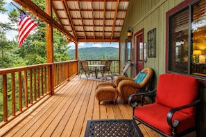 Eine Holzterrasse mit Gartenmöbeln, einer Flagge und Blick auf den Wald.