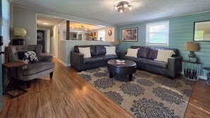 Ein Wohnzimmer mit einem dunkelbraunen Ledersofa, einem gemusterten Teppich und einer Deckenleuchte.
