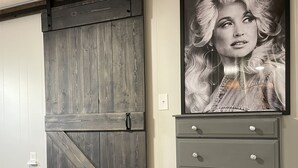 Ein Zimmer mit einer Holztür im Scheunenstil, einer grauen Kommode mit Schubladen und einem gerahmten Bild an der Wand.