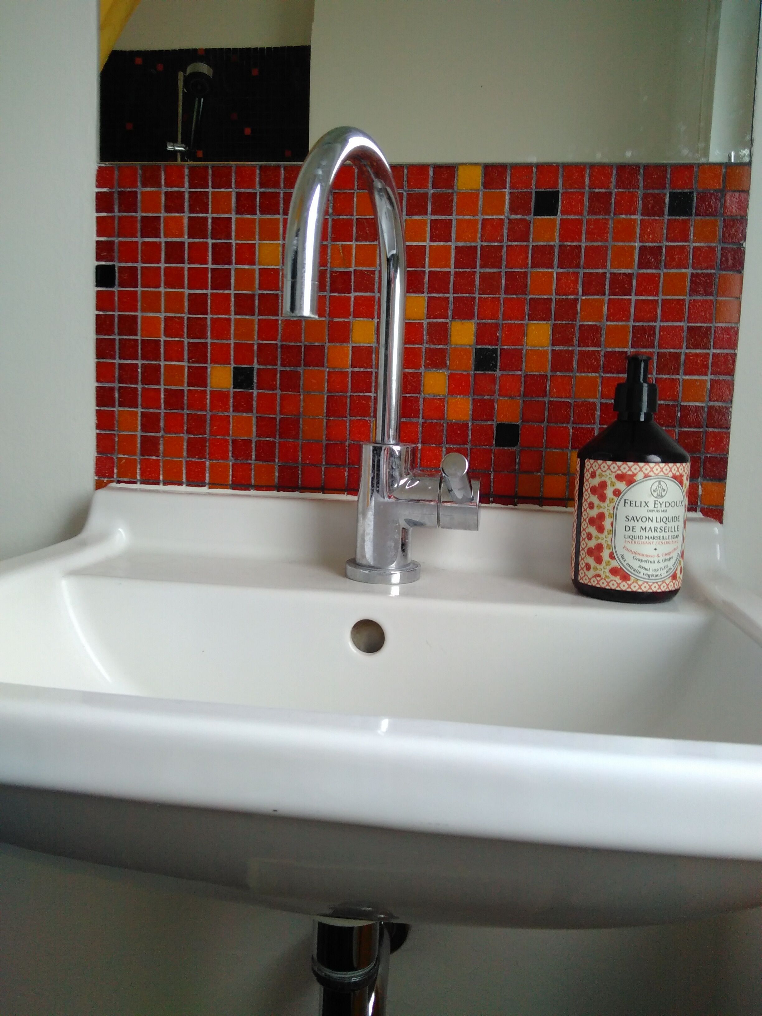 Un lavabo de salle de bain avec un robinet chromé et un flacon de savon.