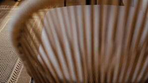 A room with a stone wall, a wooden table with a bowl of lemons, a wicker chair, and a small wooden nightstand. - Porto Nativo Split (Split)