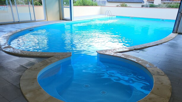 Ein Pool mit kreisförmigem Design, umgeben von einer gefliesten Terrasse.