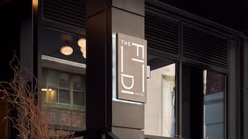 Welcome to our hotel, featuring a sleek entrance with a prominent sign and large windows offering a glimpse into our spacious lobby.