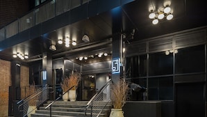 A modern building entrance with a staircase, large windows, and a sign with illuminated numbers.