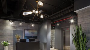 A modern reception area with a desk, a large painting, and a ceiling light fixture.