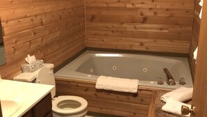 A wooden-paneled bathroom with a bathtub, toilet, and vanity. - 9 - Clean, Comfortable and Quiet Condo at the base of Jackson Creek Summit (Wakefield)