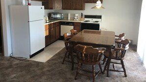A kitchen with wooden cabinets, a white refrigerator, a stove, and a dining table with chairs. - 9 - Clean, Comfortable and Quiet Condo at the base of Jackson Creek Summit (Wakefield)