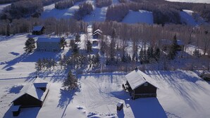 A snow-covered landscape with a cabin and a larger building, surrounded by trees and a ski slope in the background. - 9 - Clean, Comfortable and Quiet Condo at the base of Jackson Creek Summit (Wakefield)