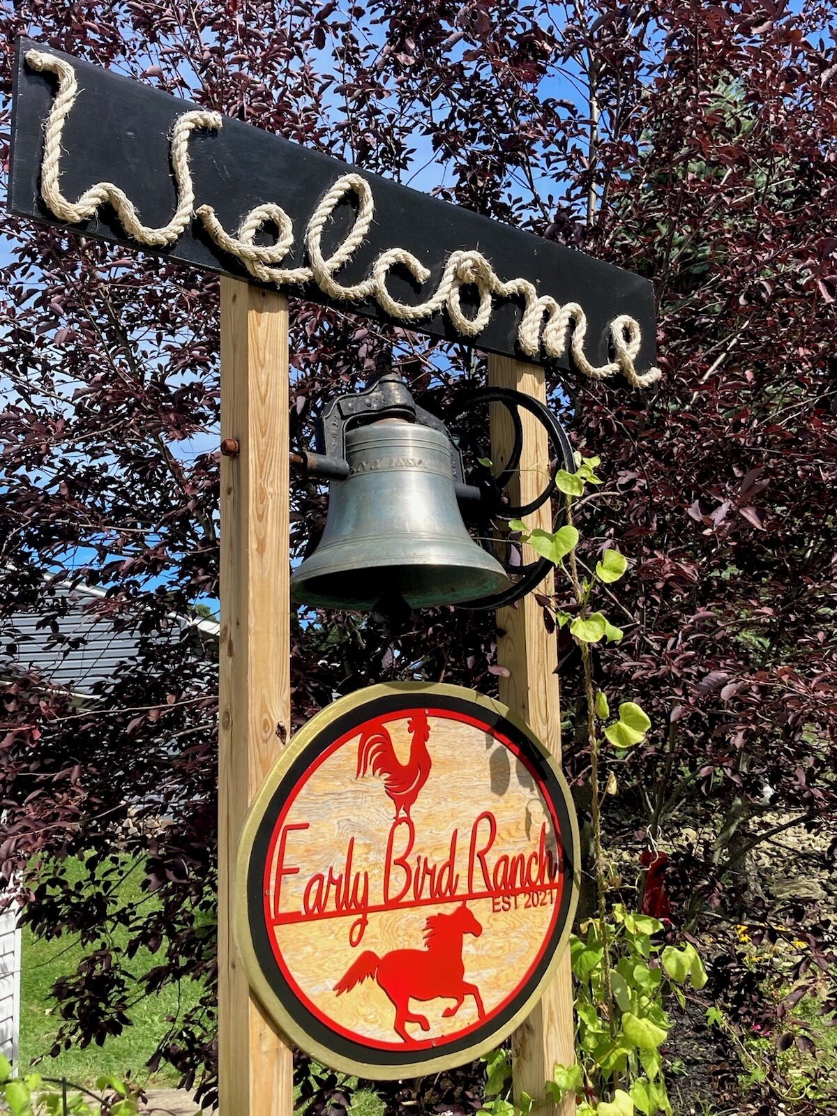 A wooden sign with a bell and a circular logo for Early Bird Ranch, established in 2021.