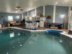 Una piscina cubierta con mesa de billar y comedor.