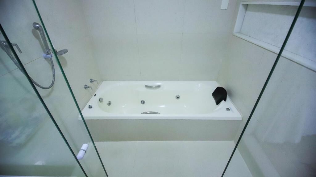 A glass-enclosed walk-in shower with a white bathtub, a handheld showerhead, and a glass door.