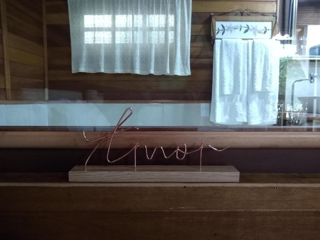 Un intérieur en bois avec une fenêtre, des rideaux et une enseigne métallique portant le mot « Eron », le tout posé sur un support en bois.