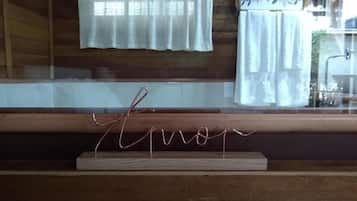Un intérieur en bois avec une fenêtre, des rideaux et une enseigne métallique portant le mot « Eron », le tout posé sur un support en bois.